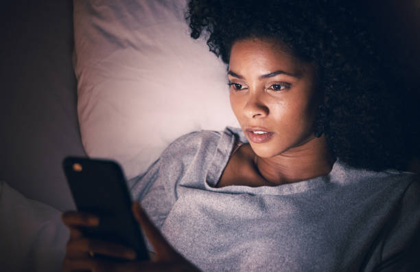 Woman using her phone at night with trouble sleeping