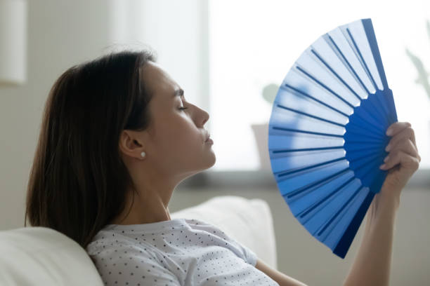 Midlife woman cooling herself during a hot flash